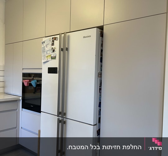 מטבח עם מקרר וארונות לבנים